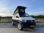 Geopend slaaphefdak met zwart doek op een Volkswagen buscamper – Meer hoofdruimte en ventilatie