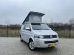 Geopend slaaphefdak met grijs doek op een Volkswagen buscamper – Meer hoofdruimte en ventilatie
